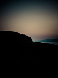 Scenic view of silhouette mountain against clear sky at sunset