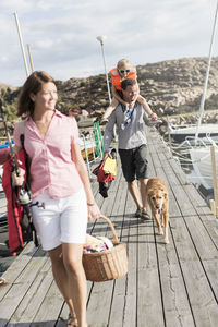 Tilt shot of family walking on jetty against sky