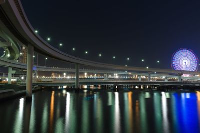 Illuminated bridge over river at night