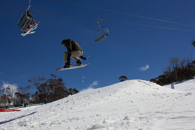 Low angle view of man doing stunt with snowboard in mid-air