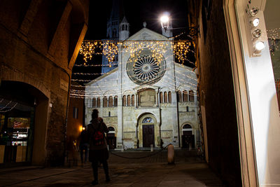 Rear view of man standing in illuminated building at night