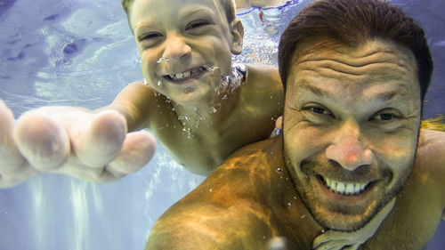 Portrait of shirtless man with father in water