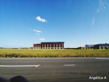 Road by building against blue sky