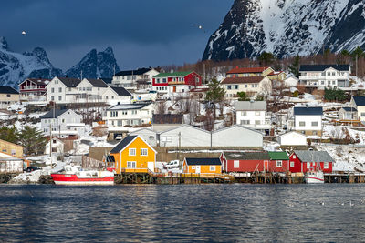 Houses by river against sky in town