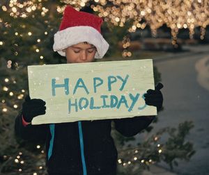 Boy holding happy holiday placard at dusk