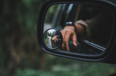 Reflection of hand on car side-view mirror