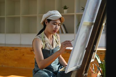 Young woman painting on canvas