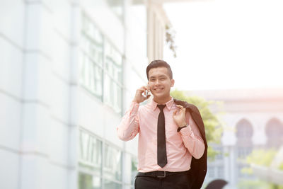 Young man using mobile phone while standing on wall