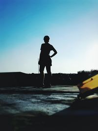 Silhouette man standing on road against clear sky during sunset