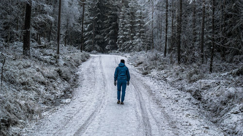 Rear view of woman walking on road in forest