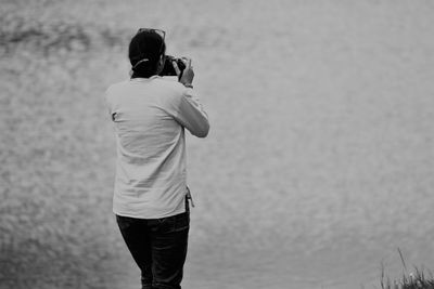 Rear view of woman photographing on beach