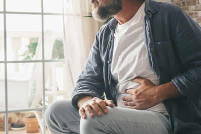 Midsection of man touching stomach at home