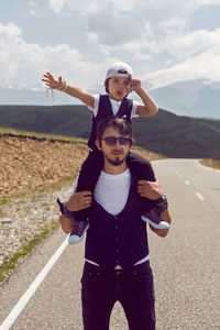 Dad and son in black vests and cap walking on the asphalt road against background of mount everest