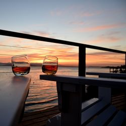 Wineglass on bench at boat deck against sky during sunset