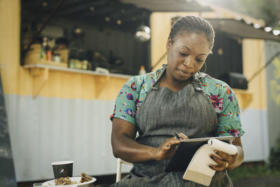 Young female entrepreneur using digital tablet against food truck