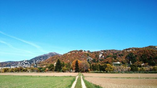 Road leading towards mountain against blue sky