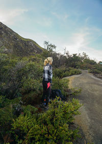 Full length of woman standing by dirt road against plants