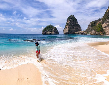 A woman is walking on the seashore at diamond beach, bali indonesia 