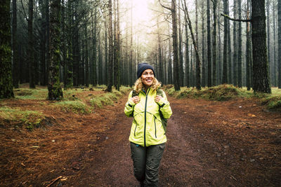 Smiling woman looking away while standing in forest