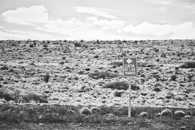 Information sign on field against sky