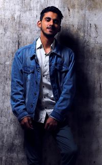 Portrait of young man standing against wall