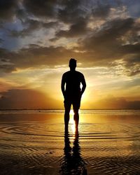 Silhouette man standing on beach against sky during sunset