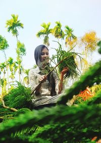Low angle view of young woman looking away against sky