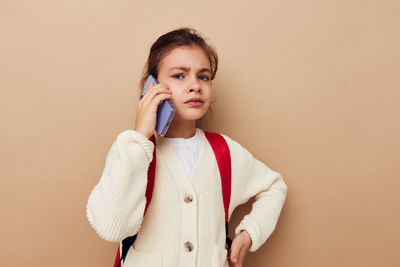 Portrait of young woman standing against wall