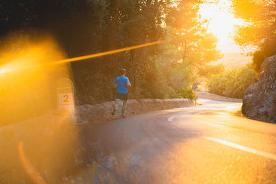 Rear view of young man jogging on road