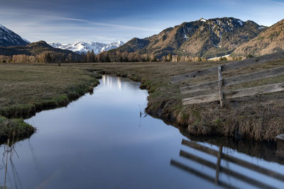 Scenic view of lake by mountains against sky