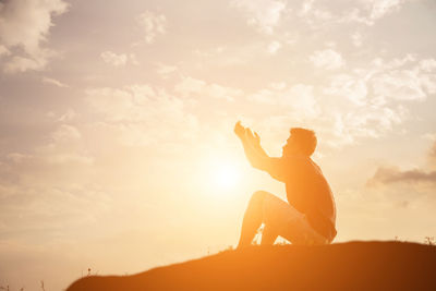 Side view of silhouette woman sitting against sky during sunset