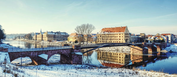 Bridge over river in city against sky during winter