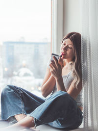 Young woman looking away while sitting on sofa at home