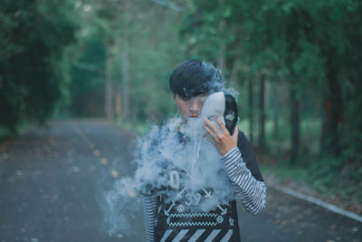 Man smoking while holding mask outdoors