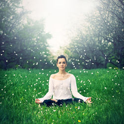 Portrait of young woman doing yoga on field amidst petals