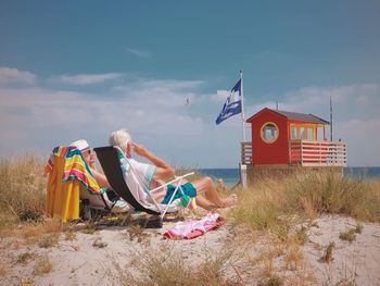 Couple relaxing at beach against sky