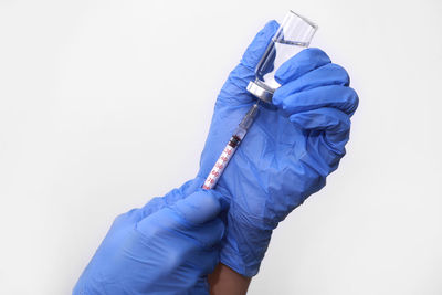 Cropped hand of doctor examining patient against white background