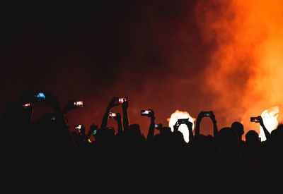 Group of silhouette people photographing at music concert