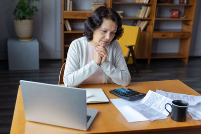 Young woman using laptop while sitting on table