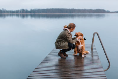 Young woman with dog on pier by lake