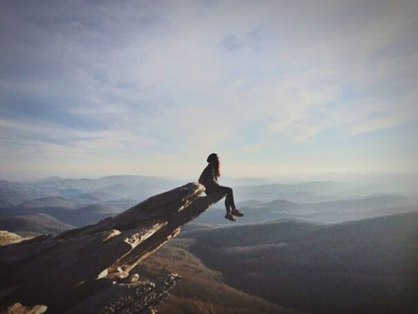 YOUNG WOMAN SITTING ON MOUNTAIN