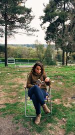 Young woman reading book while sitting on chair