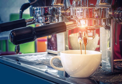 Close-up of espresso machine pouring coffee in cafe