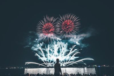 People looking at fireworks against sky