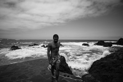 Full length of shirtless boy on beach against sky