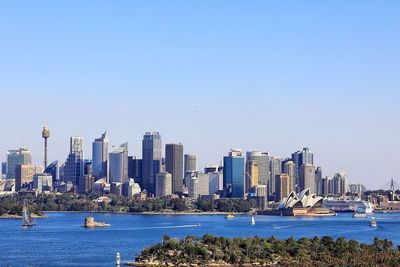 Sea by modern buildings against clear sky