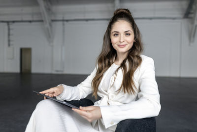 Businesswoman with tablet pc on chair at industial hall