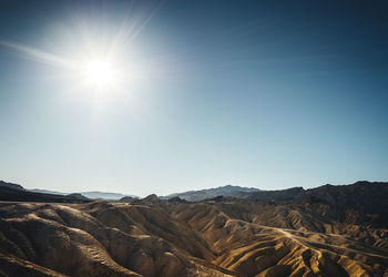 Scenic view of mountains against blue sky on sunny day