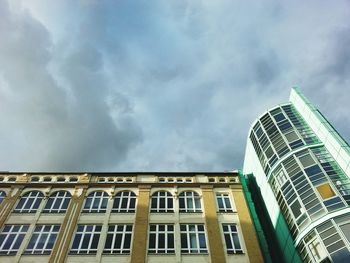 Low angle view of office building against cloudy sky