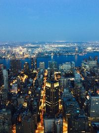 High angle view of illuminated city buildings against blue sky